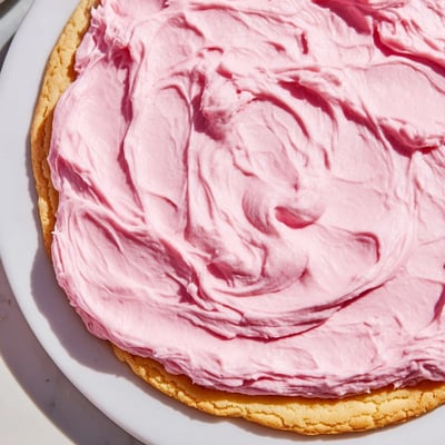 A close-up of a Giant Chilled Crumbl Sugar Cookie showing soft edges and creamy pink topping.