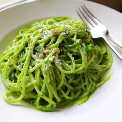 Steaming bowl of wild garlic pesto pasta garnished with freshly cracked black pepper
