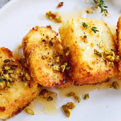 Crispy Honey Halloumi topped with fresh herbs and served warm on a plate.  